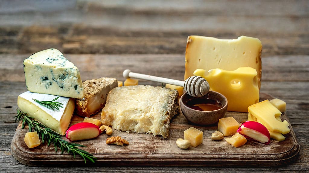 Appetizing cheese plate with honey, nuts and rosemary