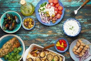 Assorted Greek dishes on rustic wooden background from above, moussaka, grilled fish, souvlaki, greek salad, steamed mussels with herbs, appetizers of Greece from above, space for text