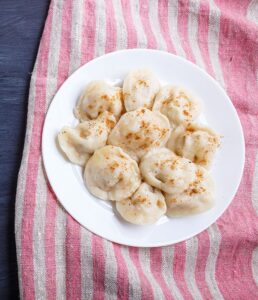 pierogi on a linen tablecloth on a black wooden background. top view, flat lay, copy space.